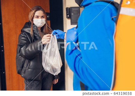 Contacless delivery service during quarantine. Man delivers food and shopping bags during isolation Contacless delivery service during quarantine. Man delivers food and shopping bags during isolation 64319038