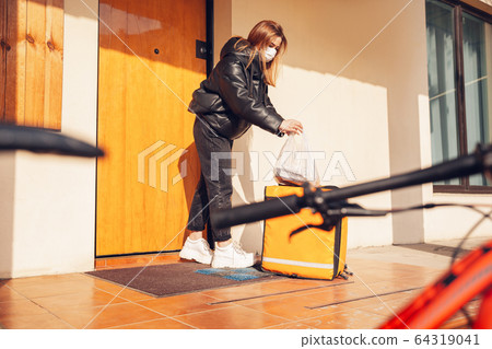 Contacless delivery service during quarantine. Man delivers food and shopping bags during isolation 64319041