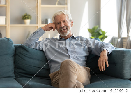 Portrait smiling mature man sitting on couch at home Portrait smiling mature man sitting on couch at home 64319042