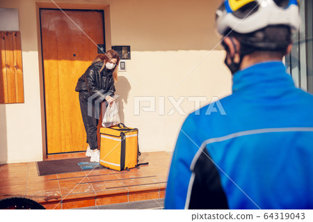 Contacless delivery service during quarantine. Man delivers food and shopping bags during isolation Contacless delivery service during quarantine. Man delivers food and shopping bags during isolation 64319043