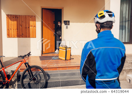 Contacless delivery service during quarantine. Man delivers food and shopping bags during isolation Contacless delivery service during quarantine. Man delivers food and shopping bags during isolation 64319044