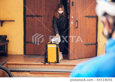 Contacless delivery service during quarantine. Man delivers food and shopping bags during isolation 64319056