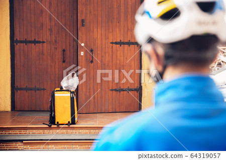 Contacless delivery service during quarantine. Man delivers food and shopping bags during isolation 64319057