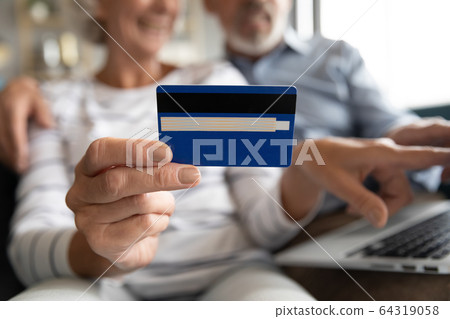 Close up mature couple paying online by plastic credit card Close up mature couple paying online by plastic credit card 64319058