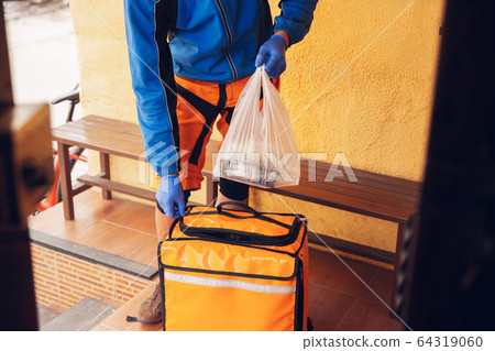 Contacless delivery service during quarantine. Man delivers food and shopping bags during isolation 64319060