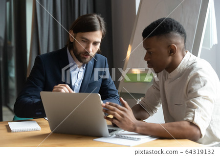 Diverse male coworkers work on laptop at briefing together Diverse male coworkers work on laptop at briefing together 64319132