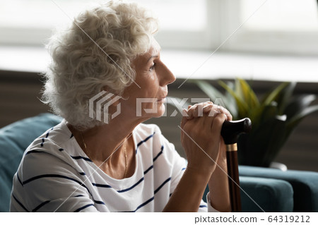 Pensive mature woman holding wooden cane, thinking about problems 64319212