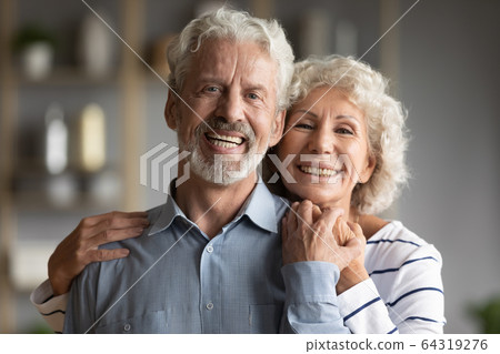 Head shot portrait smiling older man and woman hugging 64319276