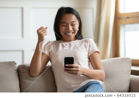 Excited asian woman hold smartphone read message feels happy Excited asian woman hold smartphone read message feels happy 64319315