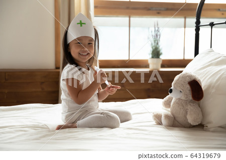 Asian girl holding syringe play with stuffed toy at home 64319679
