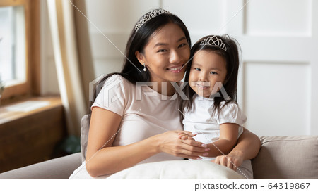 Beautiful mother cuddles adorable preschool daughter happy family portrait Beautiful mother cuddles adorable preschool daughter happy family portrait 64319867