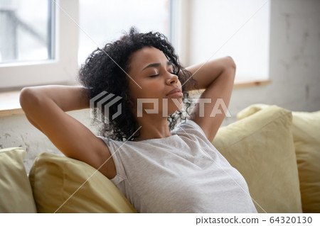 Calm african american woman with hands behind head relaxing. Calm african american woman with hands behind head relaxing. 64320130