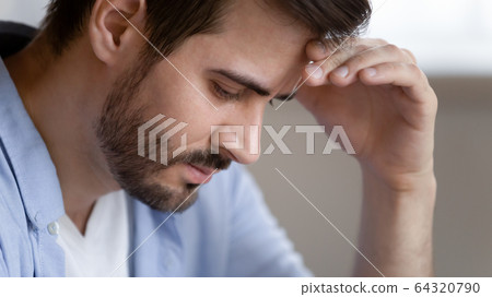Frustrated young man touching forehead, feeling depressed. Frustrated young man touching forehead, feeling depressed. 64320790