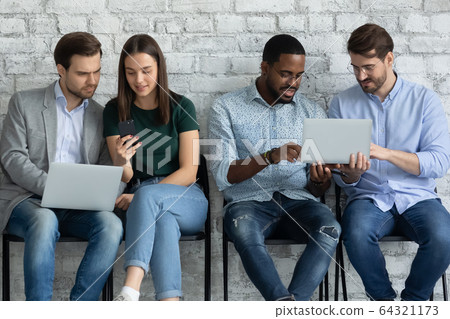 Diverse young people browsing gadgets preparing for interview in office Diverse young people browsing gadgets preparing for interview in office 64321173