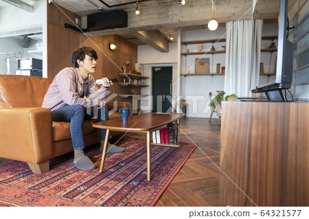 Young man with TV remote control Young man with TV remote control 64321577