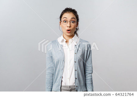 Lifestyle, people and emotions concept. Shocked, startled young asian impressed woman, stare with surprise and awe at something incredible, open mouth gasping astounded, grey background 64321764