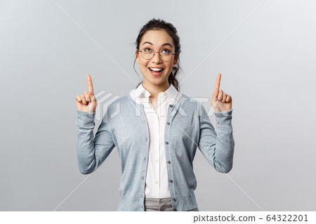 Advertisement, education and people concept. Attractive asian woman in glasses, checking out awesome promo, great deal at shop, pointing fingers up, looking at top banner smiling excited 64322201