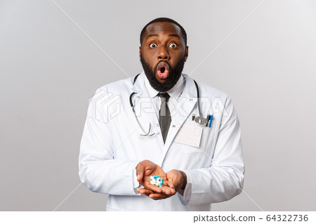 Flu, disease, healthcare and medicine concept. Astonished african-american bearded doctor in white coat, gasping wondered, look impressed camera, holding pills, recommend medication 64322736