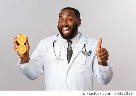 Healthcare, healthy diet and disease concept. Handsome african-american bearded doctor, physician or diatologist recommend eat fruits, showing oranges, avoid junk food, smile and thumb-up 64322888