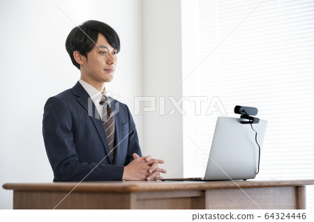 Image of a young man heading for a laptop with a webcam set for job hunting and web interview Image of a young man heading for a laptop with a webcam set for job hunting and web interview 64324446