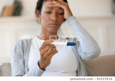 Sad african american girl hold pregnancy test 64325614