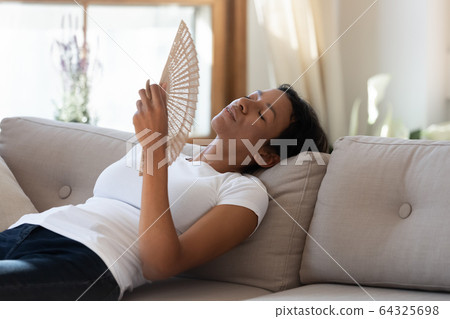 Exhausted african american woman hold fan in hand Exhausted african american woman hold fan in hand 64325698