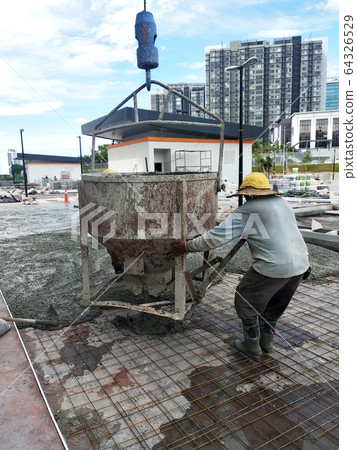 Group of construction workers pouring wet concrete using the mobile crane bucket the construction site.   64326529