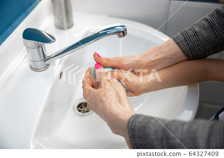 Mother washing hands her son carefully in bathroom close up. Prevention of infection and pneumonia virus spreading Mother washing hands her son carefully in bathroom close up. Prevention of infection and pneumonia virus spreading 64327409