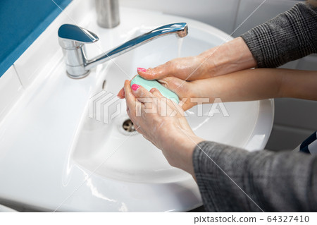 Mother washing hands her son carefully in bathroom close up. Prevention of infection and pneumonia virus spreading Mother washing hands her son carefully in bathroom close up. Prevention of infection and pneumonia virus spreading 64327410