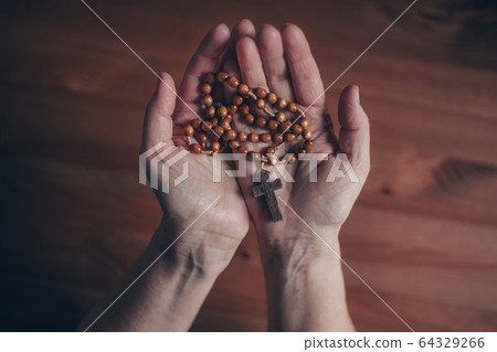 Woman praying with wooden rosary, religion concept 64329266