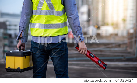 Worker man holding spirit level tool and box 64329424