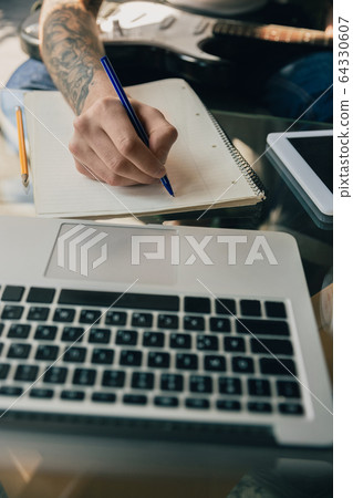 Young man studying at home during online courses or free information by hisself, close up Young man studying at home during online courses or free information by hisself, close up 64330607