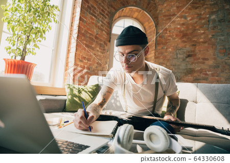 Young man studying at home during online courses or free information by hisself Young man studying at home during online courses or free information by hisself 64330608