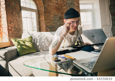Young man studying at home during online courses or free information by hisself Young man studying at home during online courses or free information by hisself 64330610