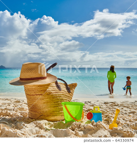 Toddler boy on beach with mother. Beach bag and 64330974