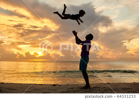 Father throws up son in the air on beach at sunset Father throws up son in the air on beach at sunset 64331253