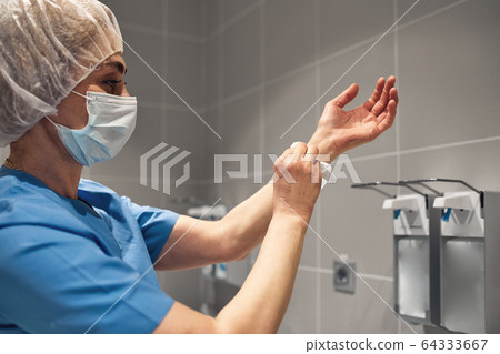 Close-up of a doctor washing his hands using a disinfectant dispenser. Close-up of a doctor washing his hands using a disinfectant dispenser. 64333667