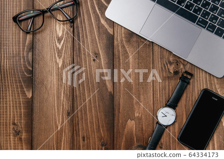Laptop, smart phone, glasses and watch on wooden table. 64334173