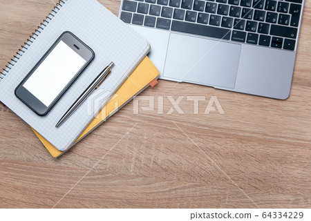 Flat lay of wooden office desk with laptop, smartphone, pen and notebook with copy space background. 64334229