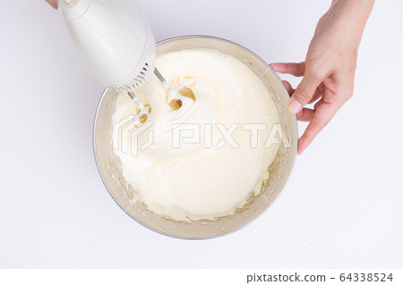 Making sweets at home, sponge dough making process Mixing eggs and sugar with a hand mixer, overhead view 64338524