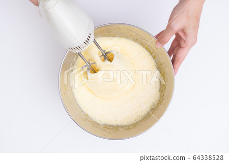 Making sweets at home, sponge dough making process Mixing eggs and sugar with a hand mixer, overhead view 64338528
