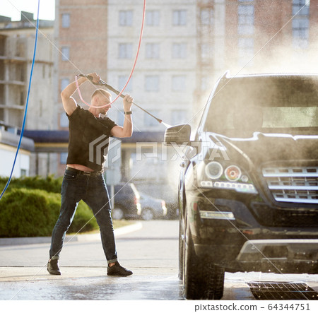 Sporty man washing his black car outdoors Sporty man washing his black car outdoors 64344751