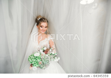 Luxury bride in white dress posing while preparing for the wedding ceremony Luxury bride in white dress posing while preparing for the wedding ceremony 64345359