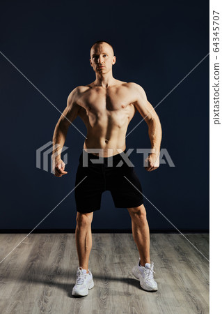 Bodybuilder demonstrates his muscles relief and strong arms, clear muscular ABS Bodybuilder demonstrates his muscles relief and strong arms, clear muscular ABS 64345707