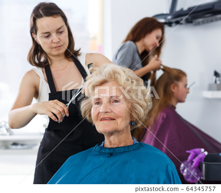 Senior lady getting haircutting Senior lady getting haircutting 64345757