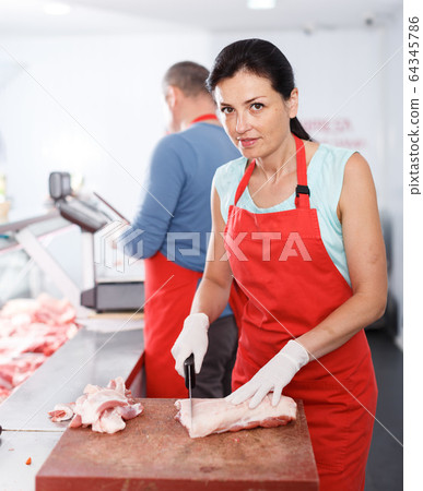 Two seller working in shop, woman cutting meat 64345786