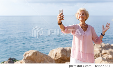 Mature woman taking selfie on beach Mature woman taking selfie on beach 64345885