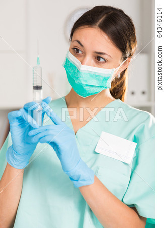 Female nurse in mask holding syringe for injection in hospital 64346114