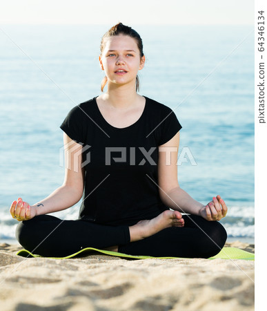 Portrait of sportswoman which is sitting and practicing asana in black T-shirt Portrait of sportswoman which is sitting and practicing asana in black T-shirt 64346134