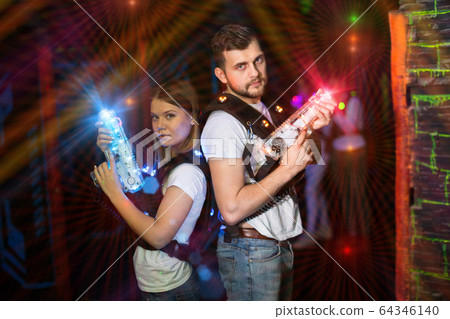 Couple standing back to back in laser beams 64346140